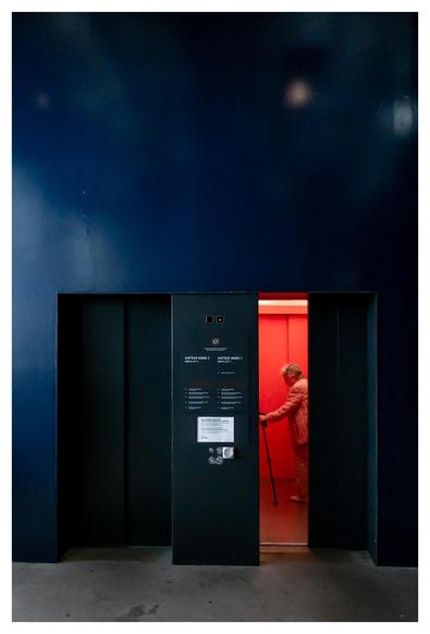 Eine ältere Dame steigt in einen rot beleuchteten Fahrstuhl in der Essener Zeche Zollverein.