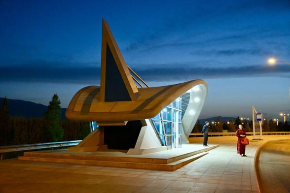 A curvy designed bus shelter at twilight