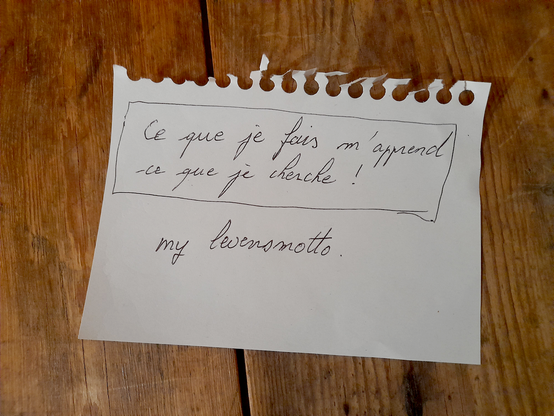 A piece of paper with a handwritten quote: "That what I do teaches me what I seek" and beneath it the words "my life motto"