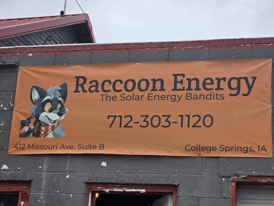 A sign for Raccoon Energy, the Solar Energy Bandits. The logo is an anthro raccoon drawn by Panda Paco.