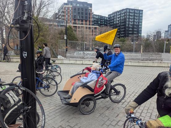 Un vélo cargo avec une banquette devant qui transporte une passagère.