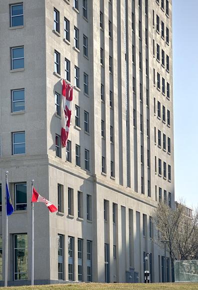 A large Canadian flag is draped out the window of the (former) Federal building, an eleven-storey Art Deco building in downtown Edmonton, Alberta.