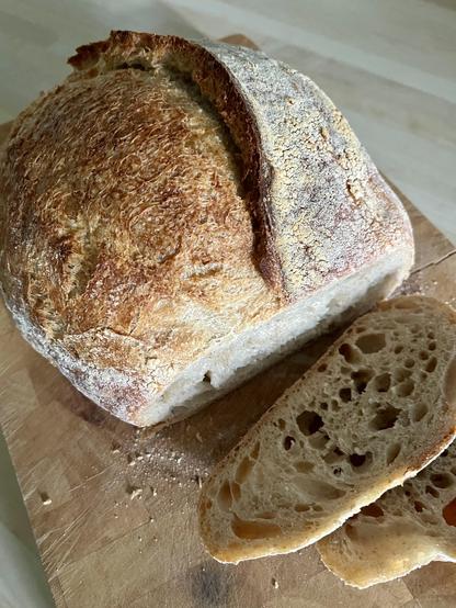Home baked sourdough loaf on bread board with two slices cut cut in the foreground
