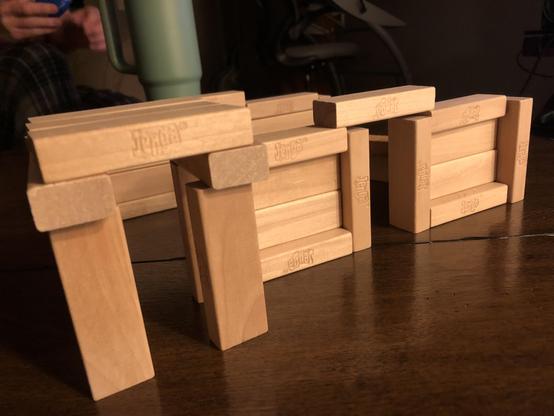 A close-up shot of a miniature house made from Jenga blocks. It has a plain door on the right and a more ornate protruding entrance on the left.