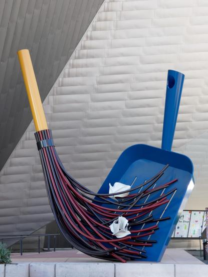 monumental sculpture of dustpan and brush, in bold colours