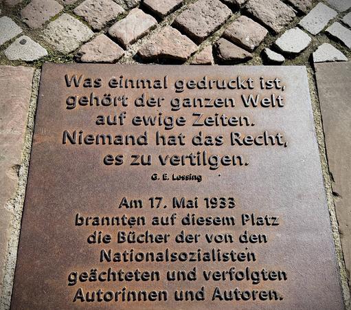 Was einmal gedruckt ist, gehört der ganzen Welt auf ewige Zeiten.
Niemand hat das Recht, es zu vertilgen.
©, E, Lessing
Am 17. Mai 1933
brannten auf diesem Platz die Bücher der von den Nationalsozialisten geächteten und verfolgten Autorinnen und Autoren.🖖