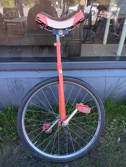 On old red unicycle.