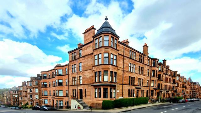 Red sandstone tenements on a corner between two Glasgow streets.