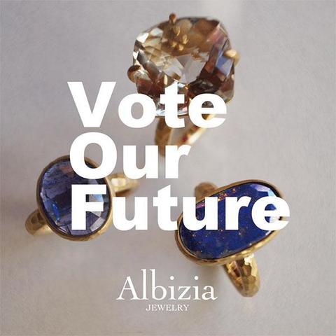 Vote Our Futureのステッカー画像です。グレーの背景に三つのリングが並び、Vote Oure Futureの文字とブランドロゴが並んでいます。正方形型です。