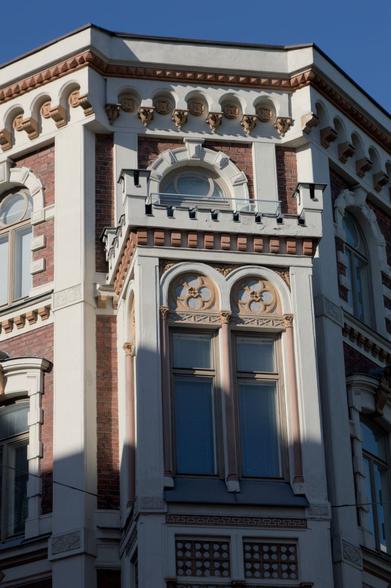 A white and red brick building front, receiving the evening sun light on a clear sky day.