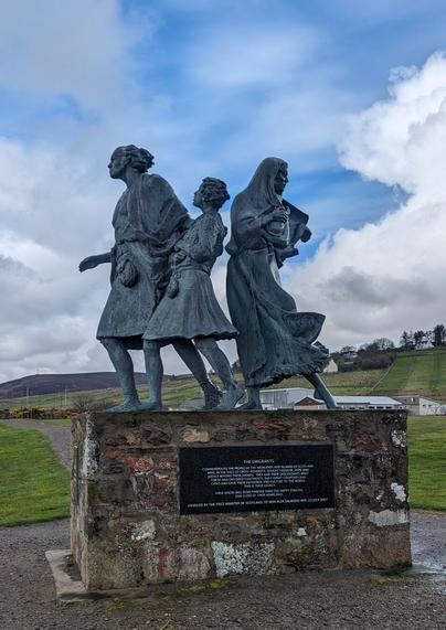 Statues of a family leaving Scotland for North America. The kilted father looks forward towards the sea, with the son looking up at him. The mother, holding a baby in her arms, looks back.
