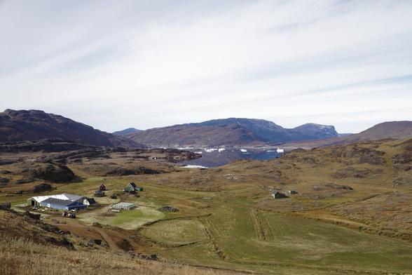 view on a farm in southern greenland with icebergs in the background
