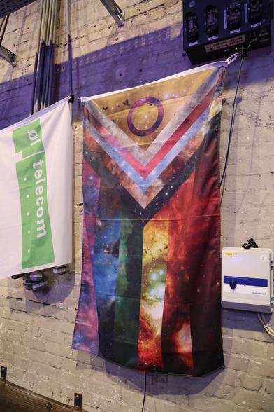 Progressive Pride flag made out of pictures from space hanging on a wall.