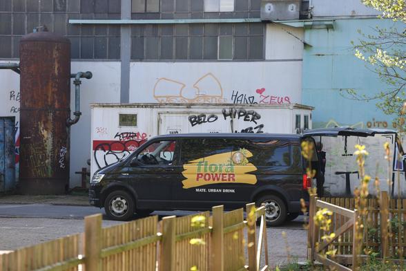 A black transporter with a Flora Mate logo and an open car trunk.