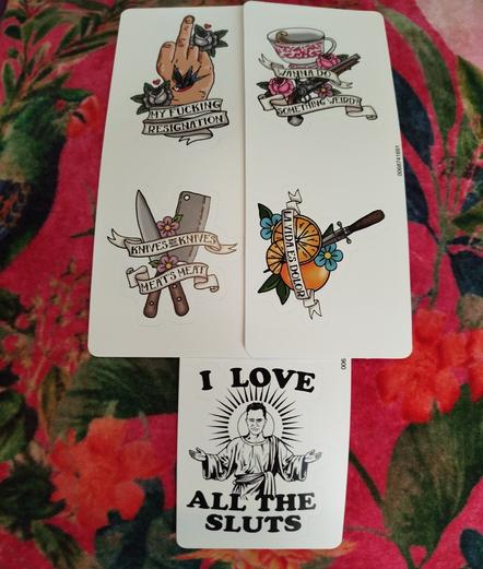 5 stickers with different designs that look like tattoo designs: A middle finger and a sparrow with the text "My fucking resignation". A gun and a cup of tea with the text "Wanna do something weird?" A couple of knives and flowers with the text "Knives are knives, meat's meat". A couple of oranges with a knife and the text "La vida es dolor". David Jenkins looking like a Messiah, with the text "I love all the sluts".