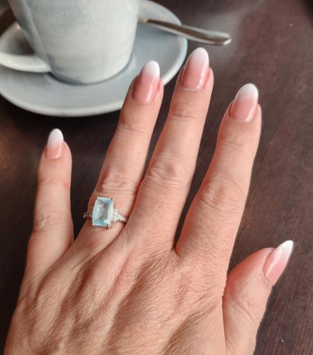A photo of a hand with pink nails and ombre white French tips