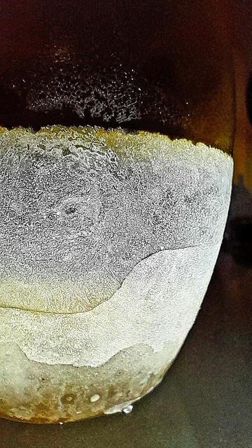 Ice condensing on the exterior of a frozen yellow glass tumbler with water frozen into the bottom, and subzero Jägermeißter, resembles an ice moon.