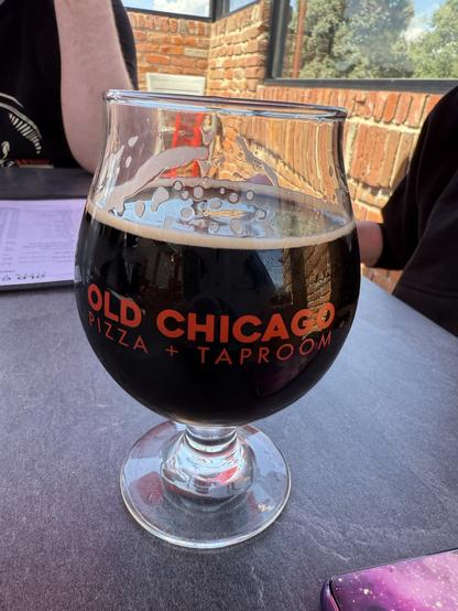 A snifter of dark beer with the Old Chicago logo in red letters