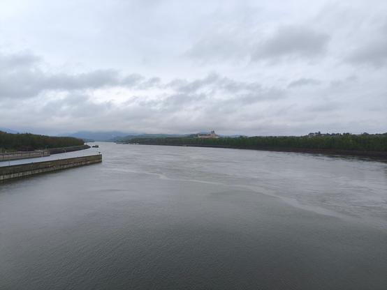 Blick zentral auf die Donau beim überqueren dieser. Der Fluss nimmt die ganze Breite des Bildes ein. Zentral dahinter ist das Stiftgebäude Melk zu sehen.