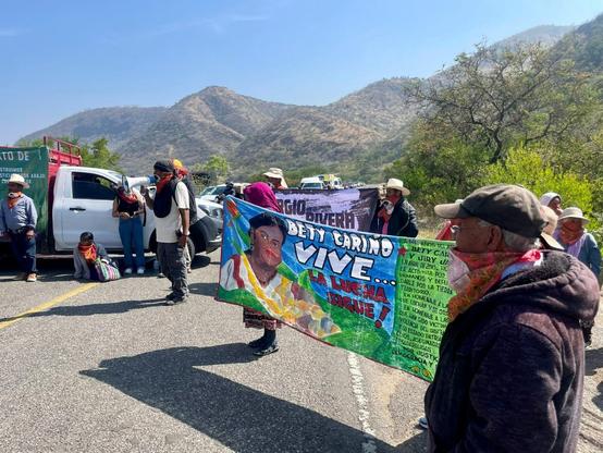 People blockade a highway holding banners demanding justice for Bety Cariño.