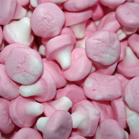 A close-up photograph of some foam mushroom sweets. They have white stalks and pink caps.