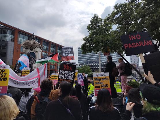 A counter-protest against the far right, with trans and Palestinian flags, and banners with "Refugees welcome", "¡No pasaran!", "Black Lives Matter", and "Migrants make the NHS"