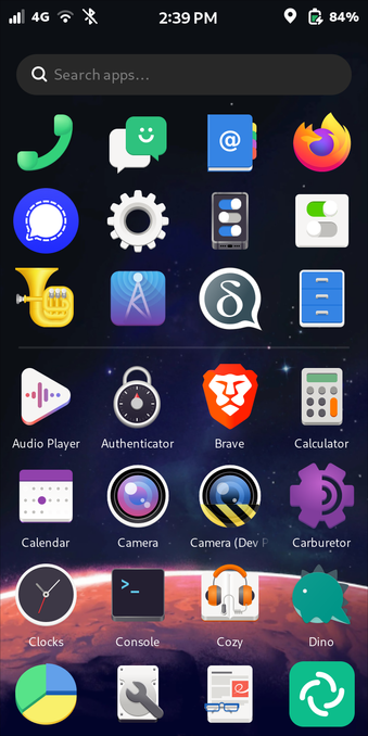 The image shows a Librem 5 Linux smartphone home screen with a dark background featuring a starry space theme. At the top, there is a status bar displaying the time as 2:39 PM, 4G connectivity, Wi-Fi, Bluetooth turned off, and a battery level of 84%. Below the status bar, there is a search bar with the text "Search apps..." in gray.

The home screen is organised into a grid of app icons. The 1st row includes a green phone icon, a green messaging icon, a blue book icon with "@" symbol, and a Firefox browser icon. 

The 2nd row features a blue Signal Messenger icon, a gear settings icon, a smartphone icon with toggle switches, 

The 3rd row features a tuba musical instrument icon, a radio tower broadcast icon, a chat bubble icon with a "d" which looks like and upside down and inverted "g" (opposite of #Google?), and a blue file drawer icon. 

The 4th row includes an audio player icon, a timing lock icon, a lion face Brave browser icon, and a calculator icon. 

The 5th row shows a calendar icon, a camera icon, a camera under construction icon, and a carburetor icon. 

The 6th row includes a clocks icon, a terminal icon, a headphones over book (audiobook) icon, and a dinosaur icon. 

The 7th row features a pie chart icon, a wrench over hard disk icon, a document with eyeglasses icon, and a green circular icon with a white swirl.

Provided by @altbot, edited. Missed by altbot: The bottom of the starry space-themed wallpaper shows the top of a Mars-like sandy planet.