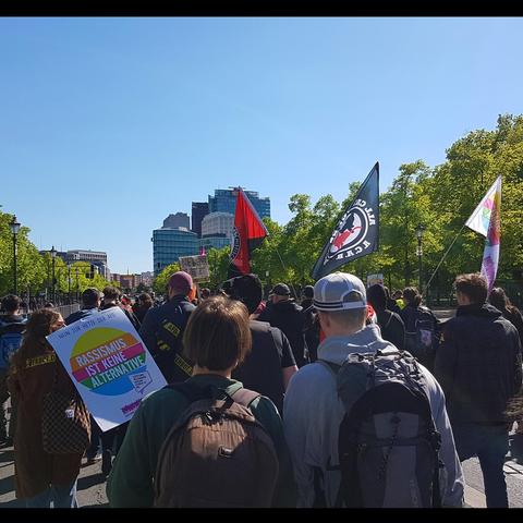 Menschen mit Fahnen und Plakaten bei der queerfeministischen Demo gegen den Nazi-Aufmarsch in Berlin.