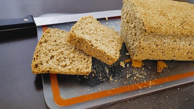 Mein fertiger Brotlaib liegt angeschnitten auf dem Schneidbrett.
Es ist ein schlankes Kastenbrot von heller goldbrauner Färbung.