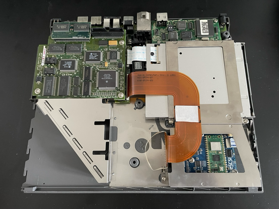 The inside of a Macintosh PoweBook 170. A BlueSCSI in installed on the hard drive slot, with a microSD card visible under the metal shielding
