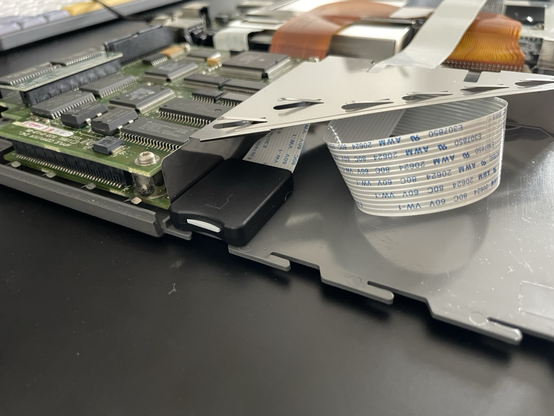 The PowerBook 170 battery slot with the socket of the microSD extension cable attached to the one side using hot glue