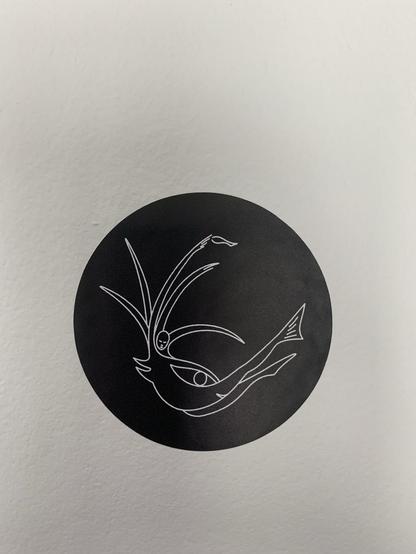 Rond noir sur fond blanc. Dans le rond on a un dessin en trait blanc d'une sorte de sirène avec des bras ou antennes.