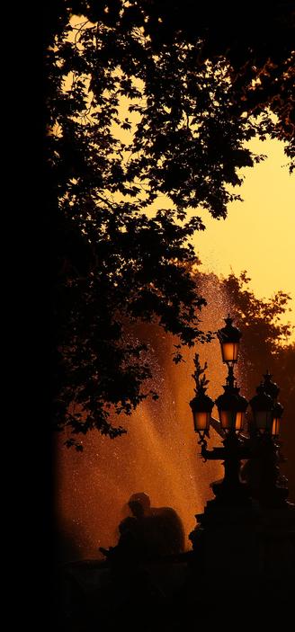 Photo au lever du jour d'une fontaine, avec un lampadaire à sa droite et un arbre à sa gauche.

La particularité de la photo c'est qu'elle est techniquement loupée. Elle est jauni, du coup la photo est noire, orange et jaune.
Et ça rend pas si mal! Mais, de base, on devrait plutôt être sur une lumière dorée, même si le reste est sombre.