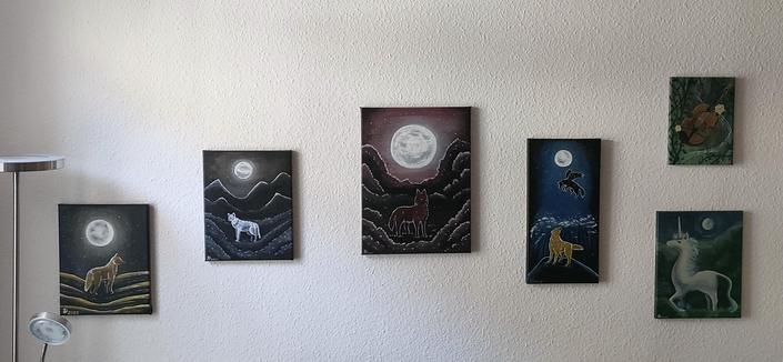 Es hängen mehrere Leinwandbilder mit unterschiedlichen Größen an der Wand. Vier von ihnen zeigen Wölfe, die nachts unter dem Vollmond stehen.
Die anderen zwei Bilder gehören nicht zu der Bildreihe und zeigen zum ein Einhorn in Mondlichtschein. Das letzte Bild ist eine Violine, darauf sind auch Verszeilen geschrieben, die ich hier aber jetzt nicht explizit erwähne. 
Alle Bilder sind im Laufe der Jahre von mir gemalt. Acryl auf Leinwand