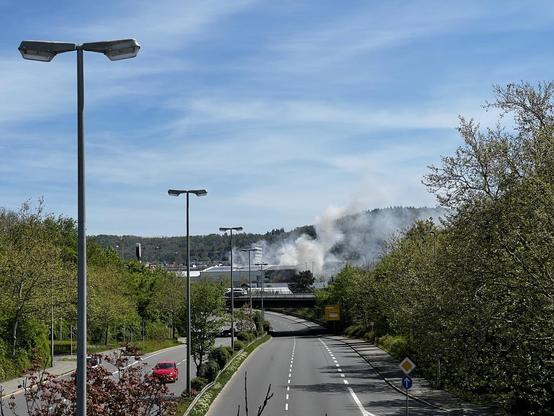 Das Bild zeigt die B28, Masten für die Beleuchtung, eine Böschung und im Hintergrund eine in  Brand stehende Halle…