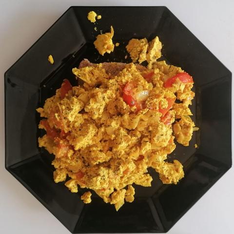 Ein schwarzer achteckiger Teller mit Rührtofu.