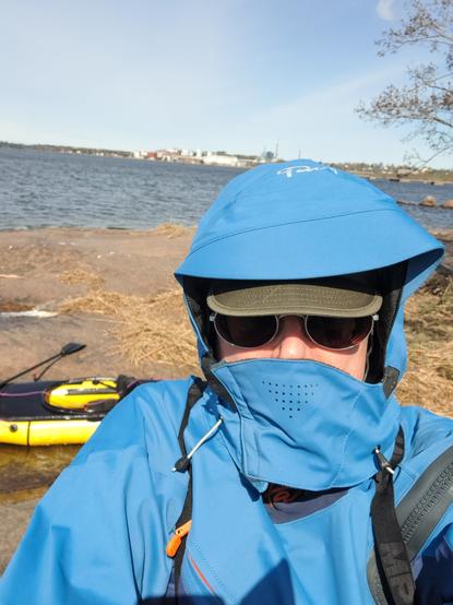 Kirjoittajan selfie, päällä Palm Fuse -kuivapuku. Taustalla packraft-kajakki ja Kotkan Keisarinsataman alue. Horistontti vinossa.