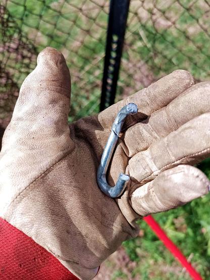The failed link in a gloved hand. The failure has occured at the weld, which shouldn't happen unless it's welded badly. There's a second crack on the opposing side that happened later, as the failed link was forced open further.