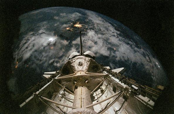 the opened shuttle bay with spacelab inside. The earth appears on horizon .