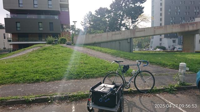 Vélo avec une carriole chargée d'outils devant la passerelle entre Grande-Delle et place de l'Europe / Cité universitaire. Passerelle sécurisée dont la voie d'accès pentue et bouchée en haut par une grosse pierre rend hasardeux voire impossible l'accès à vélo cargo, vélo chargé ou pour les débutant-es . . .