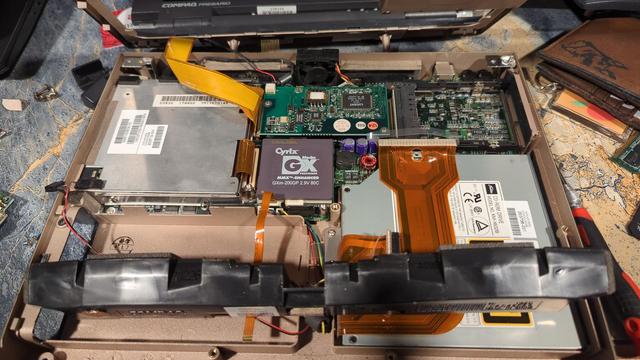 The inside of a Compaq Presario 1220. The keyboard, palm rest, hard drive, and heat sink have all been removed. The main board and CPU are visible, along with the CD and floppy drives.