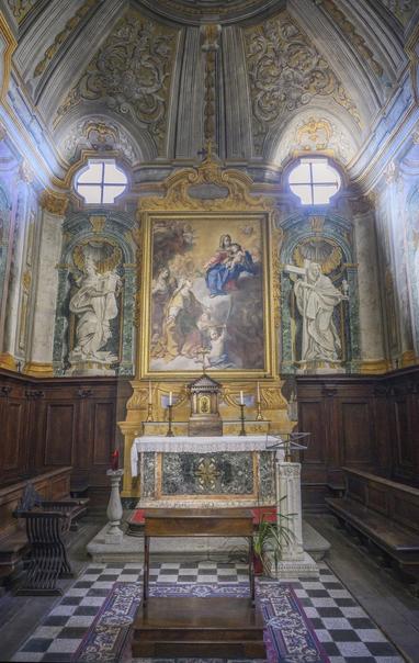 The small Baroque chapel of Santa Lucia in the Viterbo Italy cathedral. It features a domed ceiling, a large painting behind the altar, and statues on either side of the altar.