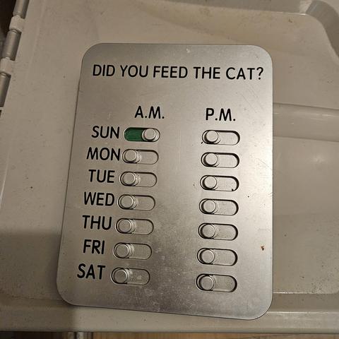 a cat feeding indicator with switches for each day am and pm. sunday am is green the rest are off.