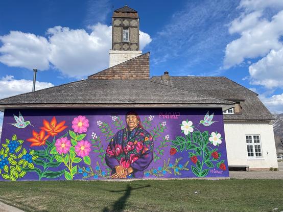 Historic Jasper firehall with purple mural wall festuring an Indigenous woman, colourful flowers and doves