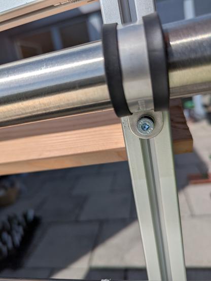 Closeup of the attachment to the balcony railing. It's a rubberised pipe cuff, connected to the planter scaffold via a slot nut.