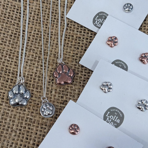 A selection of pendants and earrings in copper or silver featuring paw-print designs