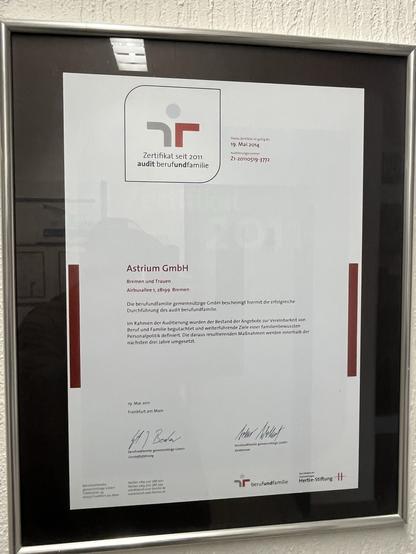 A framed certificate from "berufundfamilie" awarded to Astrium GmbH, dated May 19, 2011. The certificate acknowledges successful participation in the audit designed for work-life balance, featuring official signatures and a logo.