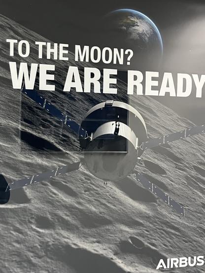 A promotional graphic featuring a spacecraft hovering above the lunar surface, with the Earth visible in the background. The text reads "TO THE MOON? WE ARE READY" and includes the Airbus logo.