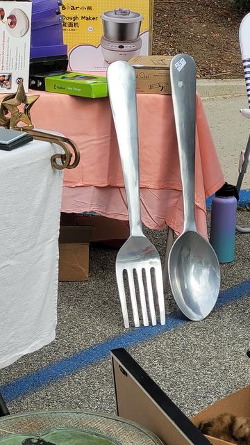 Giant fork and spoon leaning against a table