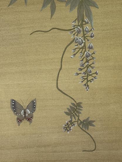 Chinesische Seidentapete. Von rechts oben hängt eine Glyzinienranke mit Blüten herab. Links unten sieht man einen Schmetterling.